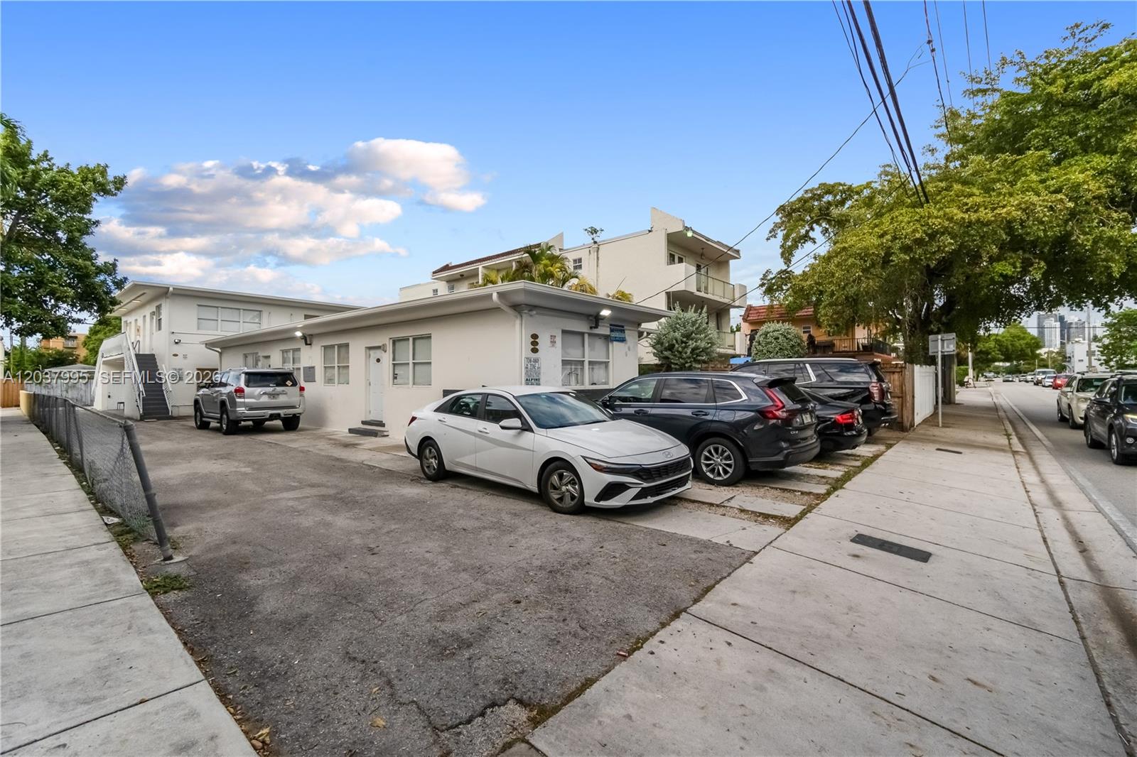 A white single-story building features a paved parking lot with several parked cars — 1131 SW 7th St, Miami FL 33130, MIAMI, FL