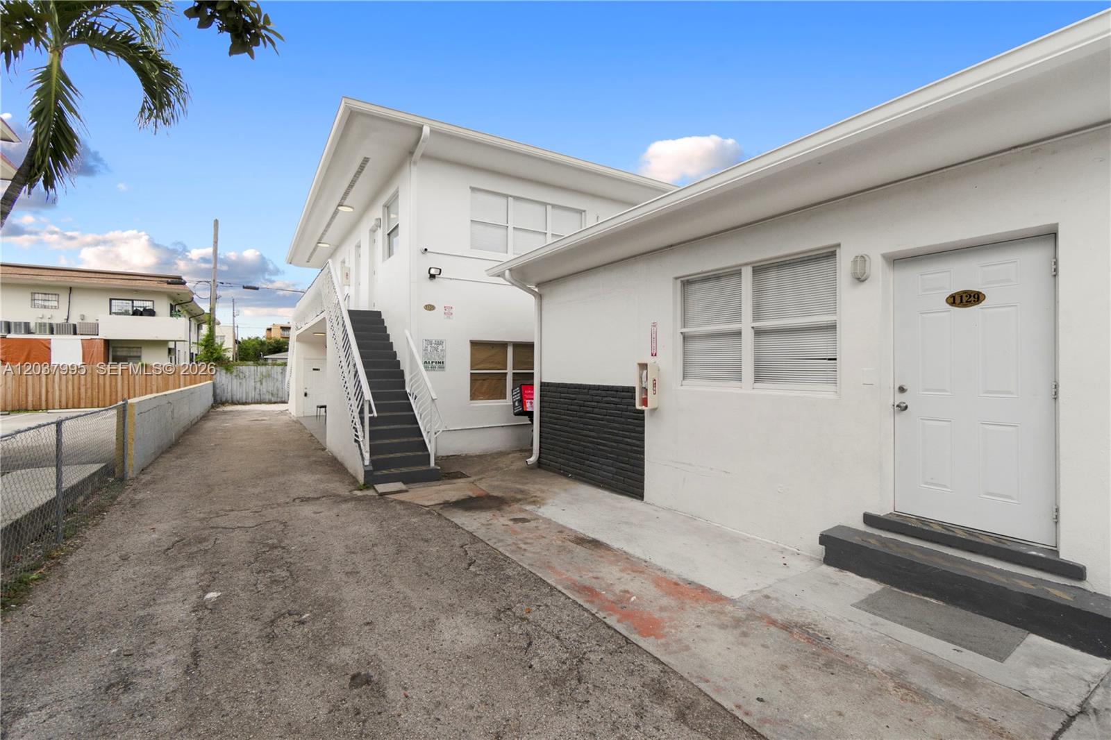 The exterior view shows a white two-story building with an outdoor staircase and a paved driveway — 1131 SW 7th St, Miami FL 33130, MIAMI, FL