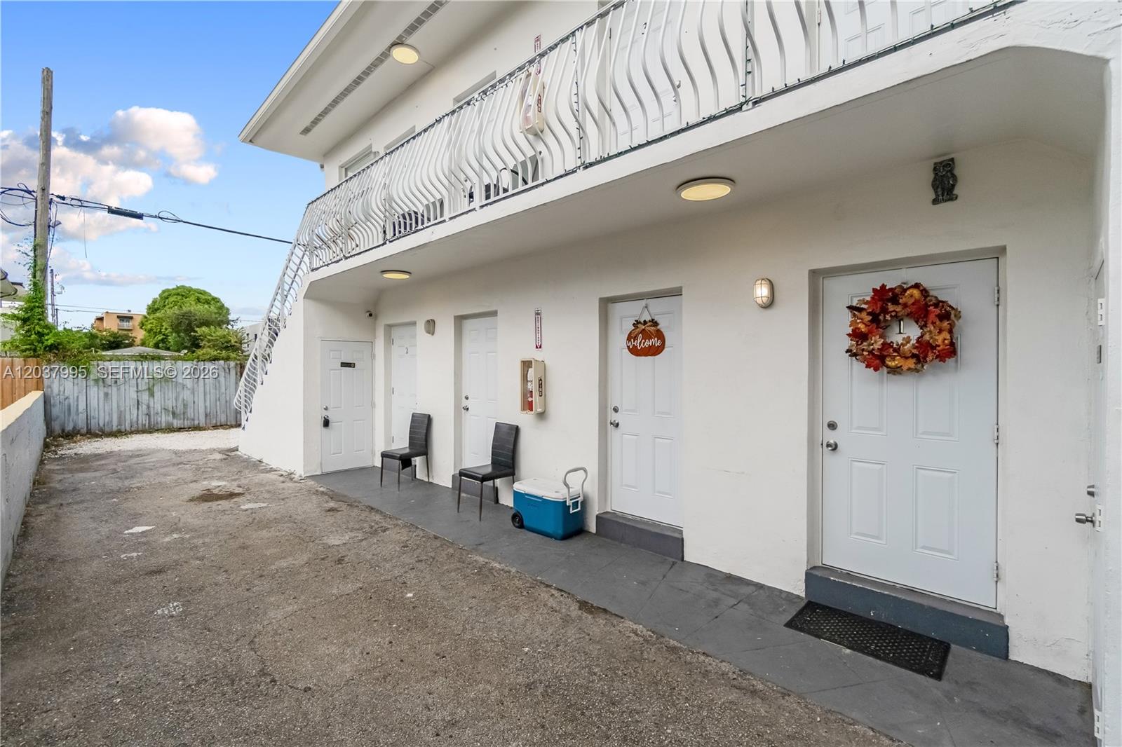 The exterior of a two-story white building features multiple doors, a balcony, and chairs — 1131 SW 7th St, Miami FL 33130, MIAMI, FL