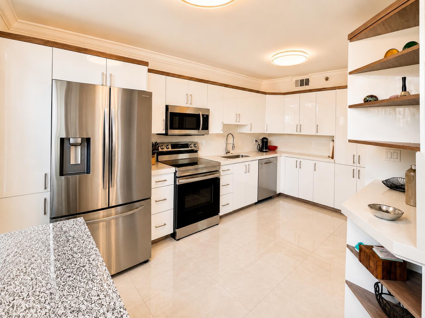 A modern kitchen features white cabinets, stainless steel appliances, and a granite-topped island — 7170 PROMENADE Drive # 101, Boca Raton FL 33433, BOCA RATON, FL