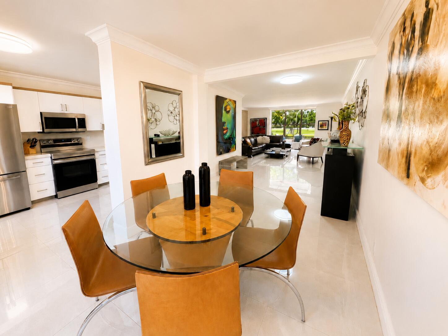 A dining area with a glass table and tan chairs opens into a modern living room — 7170 PROMENADE Drive # 101, Boca Raton FL 33433, BOCA RATON, FL
