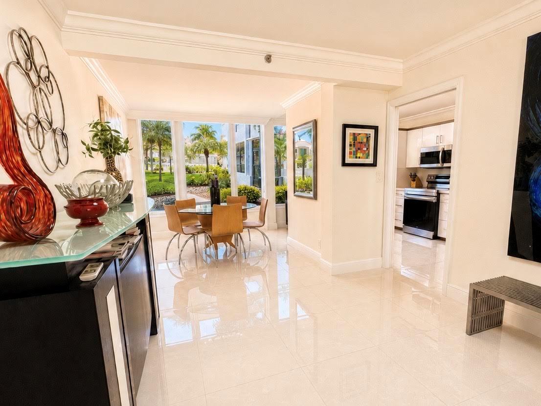 A bright dining area with a glass table, light wood chairs, and tile flooring — 7170 PROMENADE Drive # 101, Boca Raton FL 33433, BOCA RATON, FL