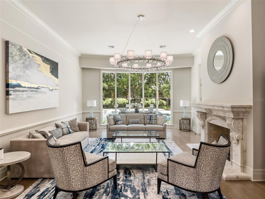 A living room features a fireplace, a large chandelier, two sofas, and two patterned armchairs — 9921 LAKE LOUISE DRIVE, WINDERMERE, FL