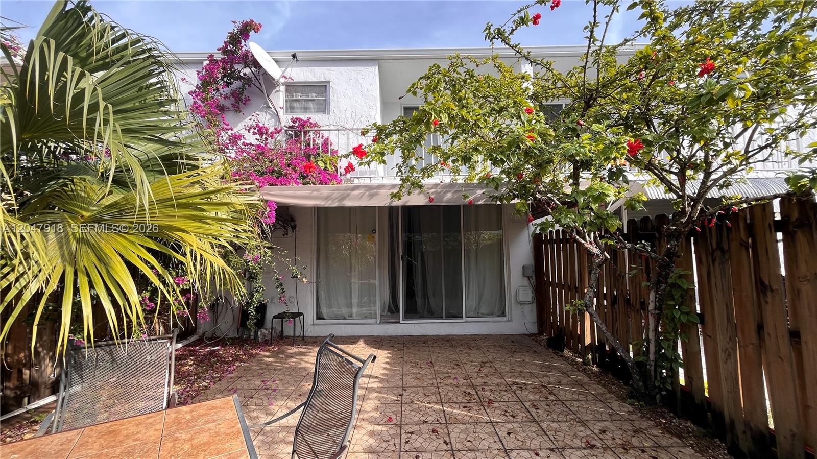 A paved patio features a sliding glass door, a retractable awning, and surrounding tropical landscaping — 807 NE 27th Ave # 807, Hallandale Beach FL 33009, HALLANDALE BEACH, FL