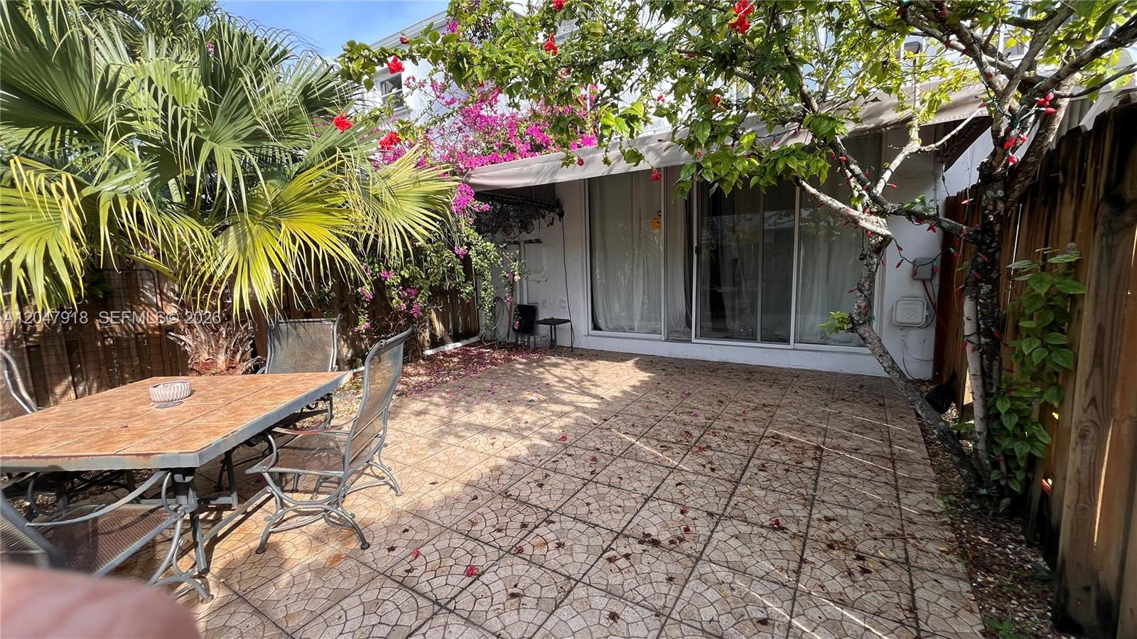 A paved patio features a dining set, a palm tree, and flowering vines against a house — 807 NE 27th Ave # 807, Hallandale Beach FL 33009, HALLANDALE BEACH, FL