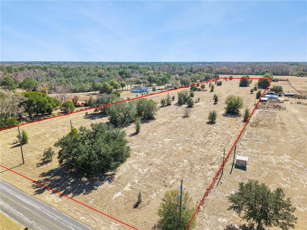 An aerial view shows a large, dry, grassy lot outlined in red next to a road — GREEN SWAMP ROAD, CLERMONT, FL