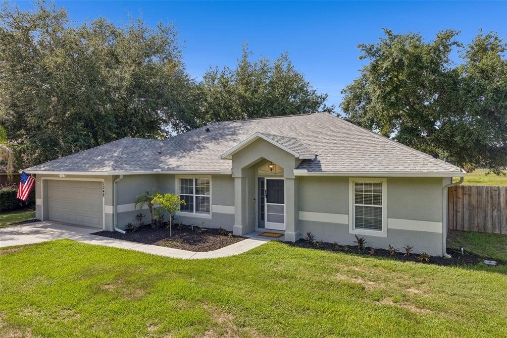 A single-story house with a gray stucco exterior, a two-car garage, and a shingled roof — 1348 GOLDEN POND DRIVE, MINNEOLA, FL