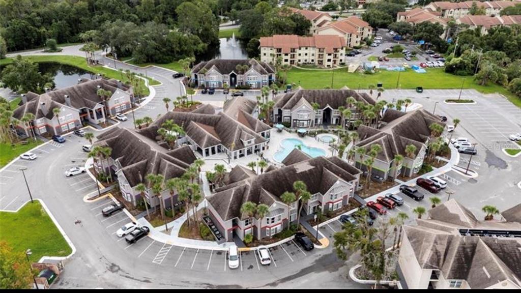 An aerial view of a multi-building apartment complex with a central swimming pool and parking — 3100 PARKWAY BOULEVARD UNIT 422, KISSIMMEE, FL