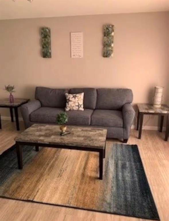 A living room features a gray sofa, a patterned area rug, and three wall decorations — 3100 PARKWAY BOULEVARD UNIT 422, KISSIMMEE, FL