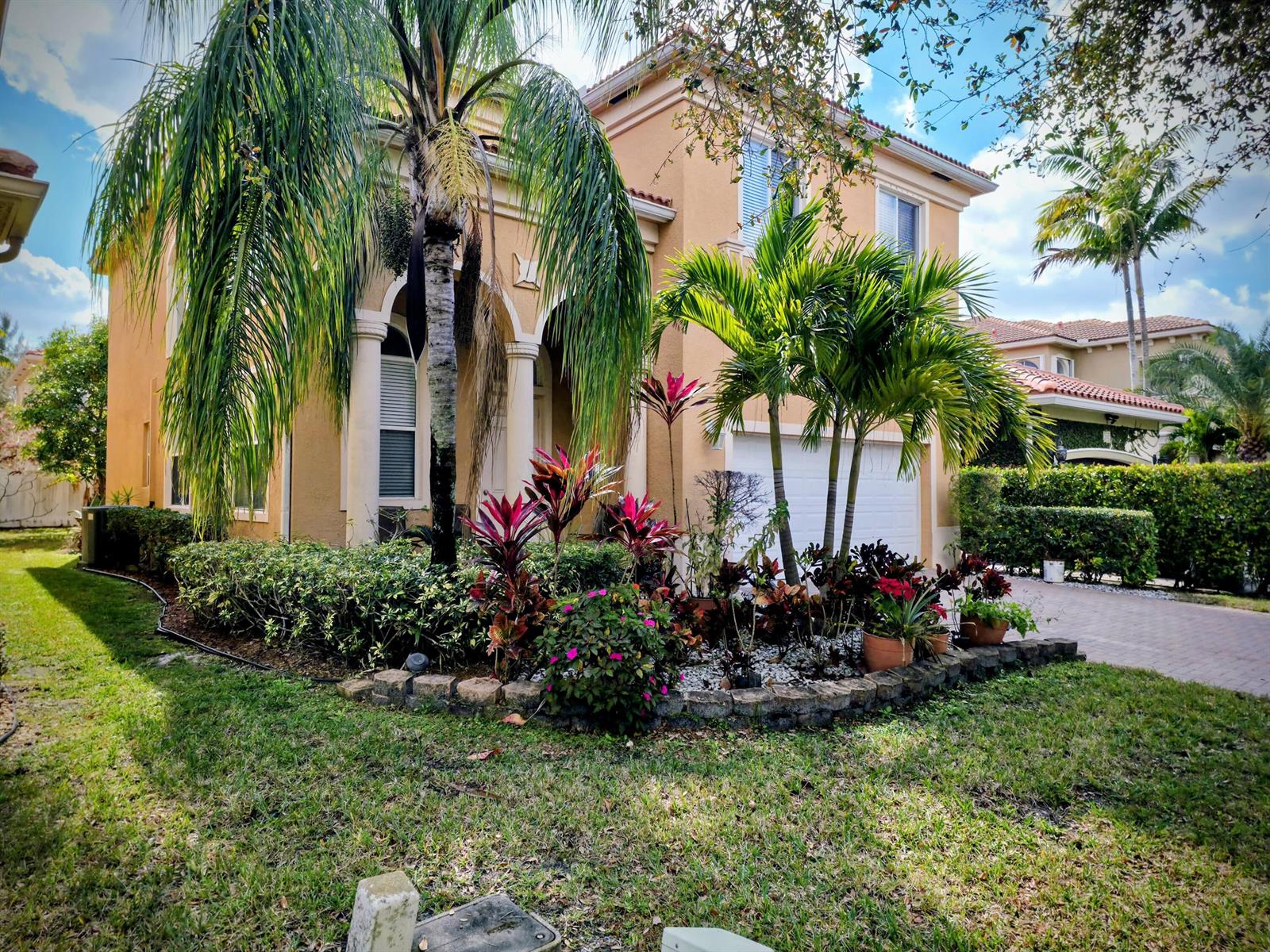 A two-story tan stucco house features a palm tree and a landscaped front garden bed — 236 Gazetta Way, West Palm Beach FL 33413, WEST PALM BEACH, FL