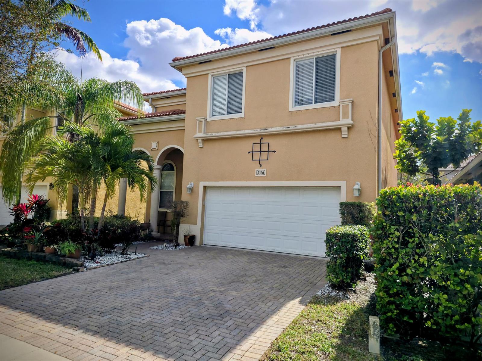 A two-story tan stucco house with a white garage door and a paved driveway — 236 Gazetta Way, West Palm Beach FL 33413, WEST PALM BEACH, FL