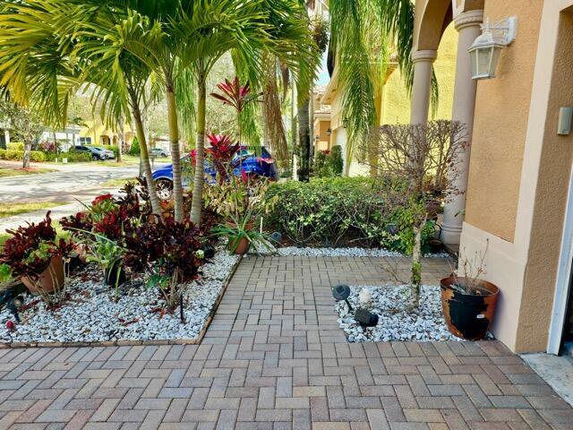 A paved walkway leads to the entrance of a house with landscaping and palm trees — 236 Gazetta Way, West Palm Beach FL 33413, WEST PALM BEACH, FL