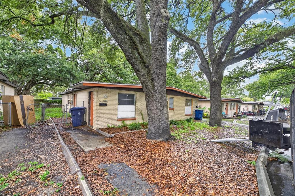 A single-story brick building sits beneath large oak trees with a paved driveway and yard — 8726 & 8728 N 48TH STREET, TAMPA, FL
