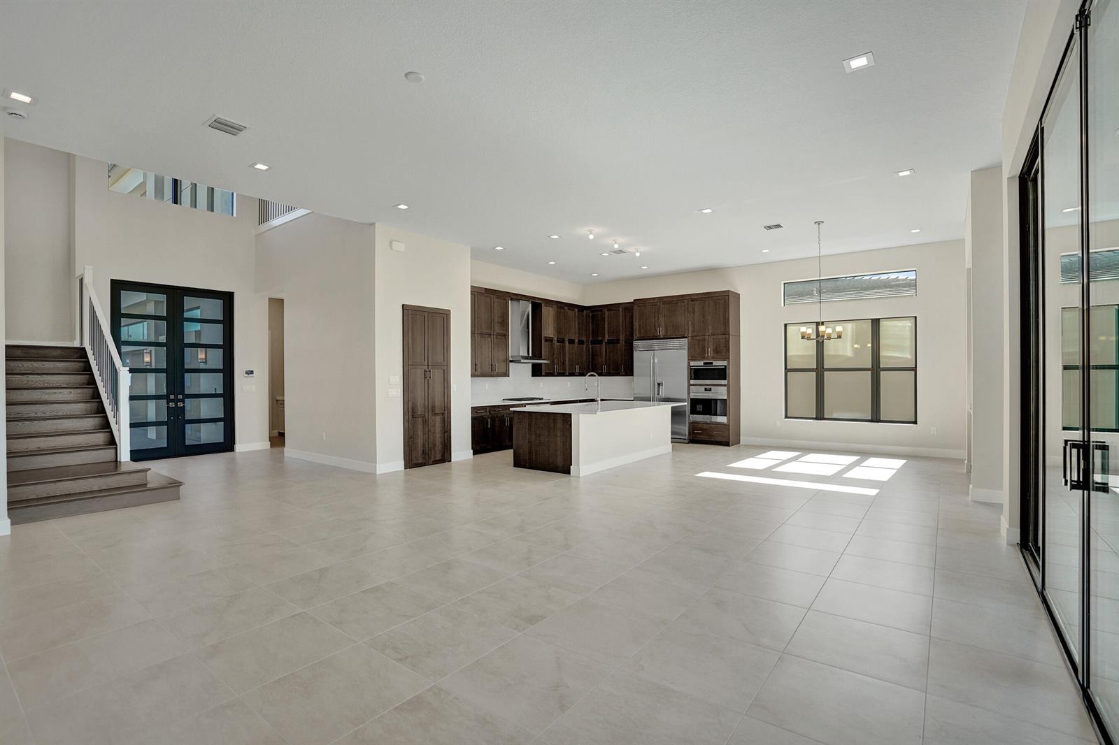 An open-concept kitchen and living area featuring dark wood cabinets, an island, and tile flooring — 9547 Riverside Park Drive, Boca Raton FL 33434, BOCA RATON, FL