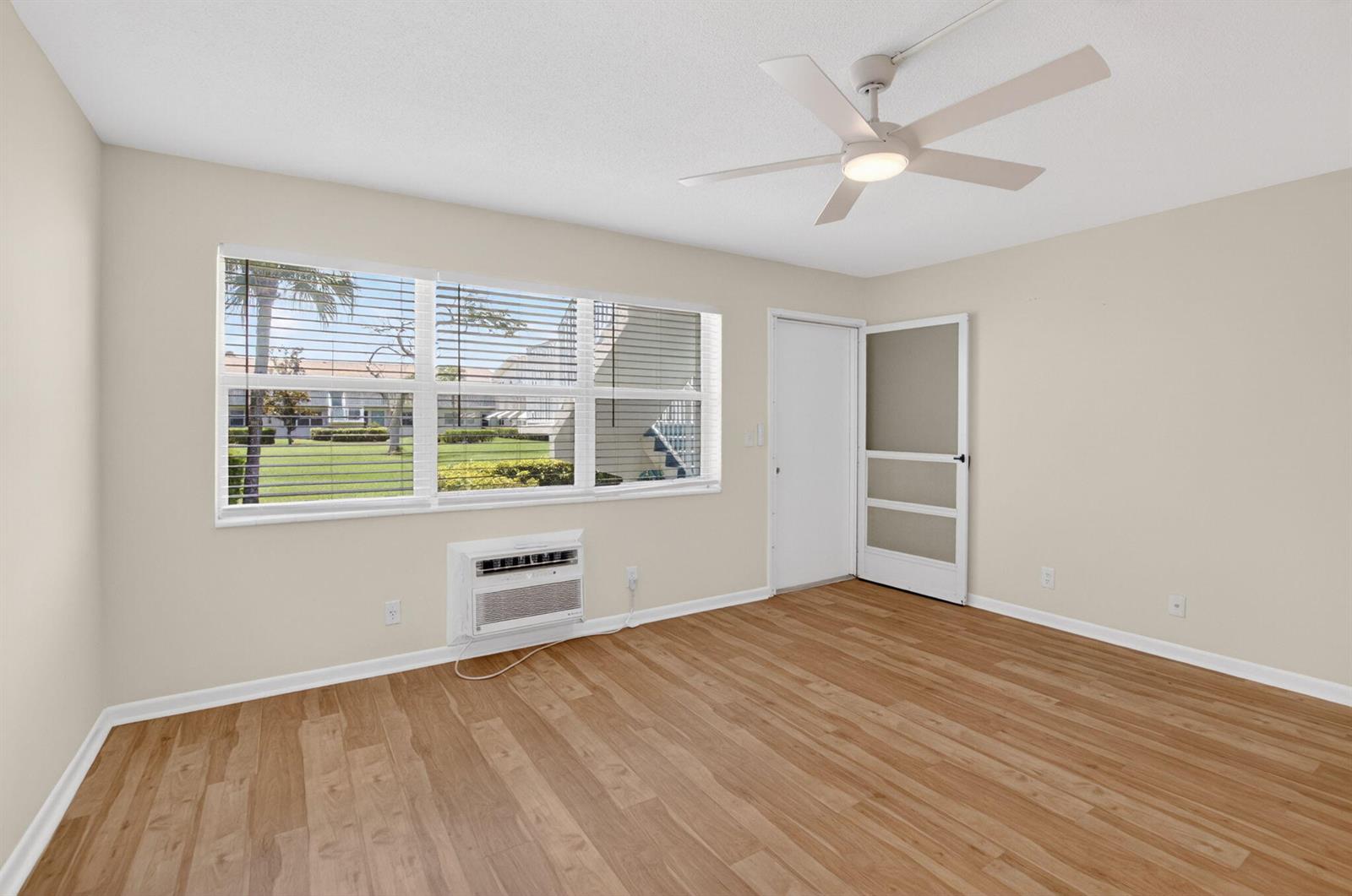 An empty room with light wood-look flooring, a ceiling fan, a window, and a door — 660 Horizon W # 107, Boynton Beach FL 33435, BOYNTON BEACH, FL