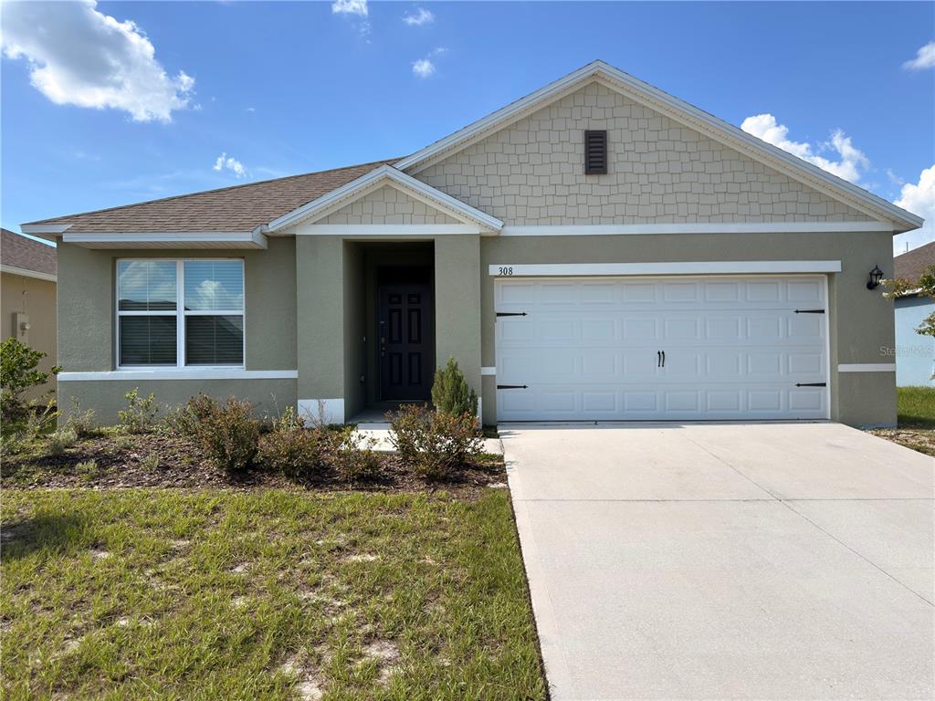 A single-story house with a beige stucco exterior, a two-car garage, and a shingled roof — 308 SOFIA LANE, LAKE ALFRED, FL