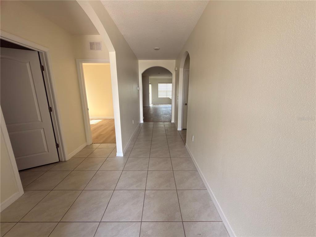 A tiled hallway leads to an arched doorway opening into a room with wood flooring — 308 SOFIA LANE, LAKE ALFRED, FL