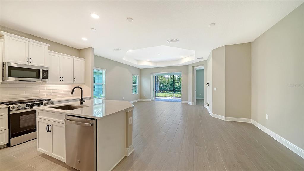 A modern kitchen with white cabinets and a center island opens into a spacious living area — 2324 BLUE MAHOE LANE, SARASOTA, FL