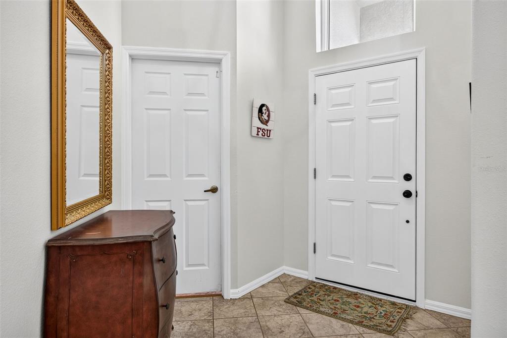 An entryway features a tiled floor, a wooden dresser with a mirror, and two doors — 10737 AYRSHIRE DRIVE, TAMPA, FL