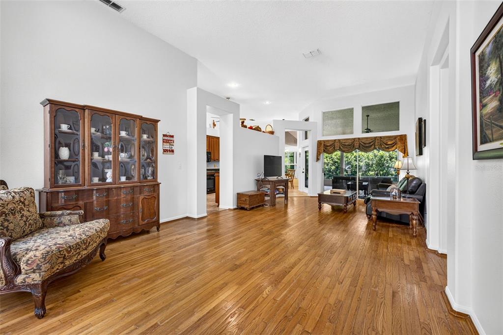 A living room with hardwood floors, a large wooden hutch, and a sliding glass door — 10737 AYRSHIRE DRIVE, TAMPA, FL