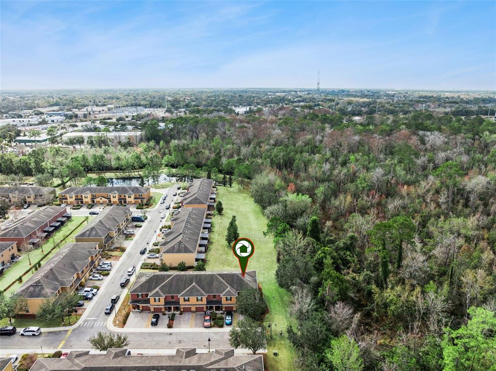 An aerial view shows a multi-unit residential building with a green marker on its roof — 601 JOYFUL BLOSSOM PLACE, LONGWOOD, FL