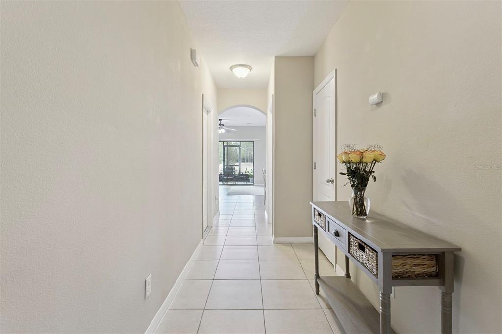 A tiled hallway leads toward an arched doorway opening into a bright living space — 601 JOYFUL BLOSSOM PLACE, LONGWOOD, FL