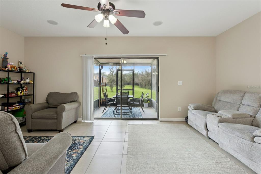 A living room features tile floors, a ceiling fan, and sliding doors opening to a patio — 601 JOYFUL BLOSSOM PLACE, LONGWOOD, FL