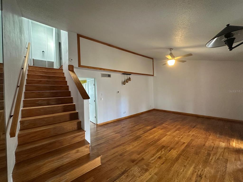 A living room with hardwood floors, a wooden staircase, and a ceiling fan — 5419 SWEETWATER TERRACE CIRCLE UNIT 3-20, TAMPA, FL