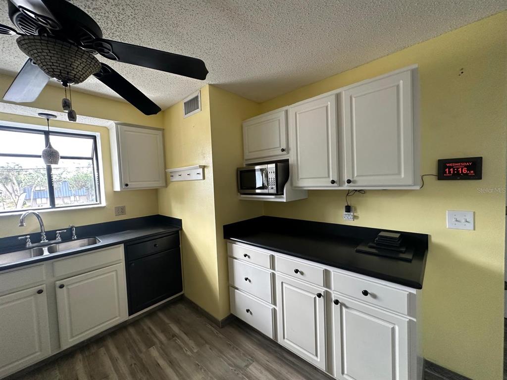A kitchen features white cabinets, black countertops, a ceiling fan, and a window above the sink — 5419 SWEETWATER TERRACE CIRCLE UNIT 3-20, TAMPA, FL