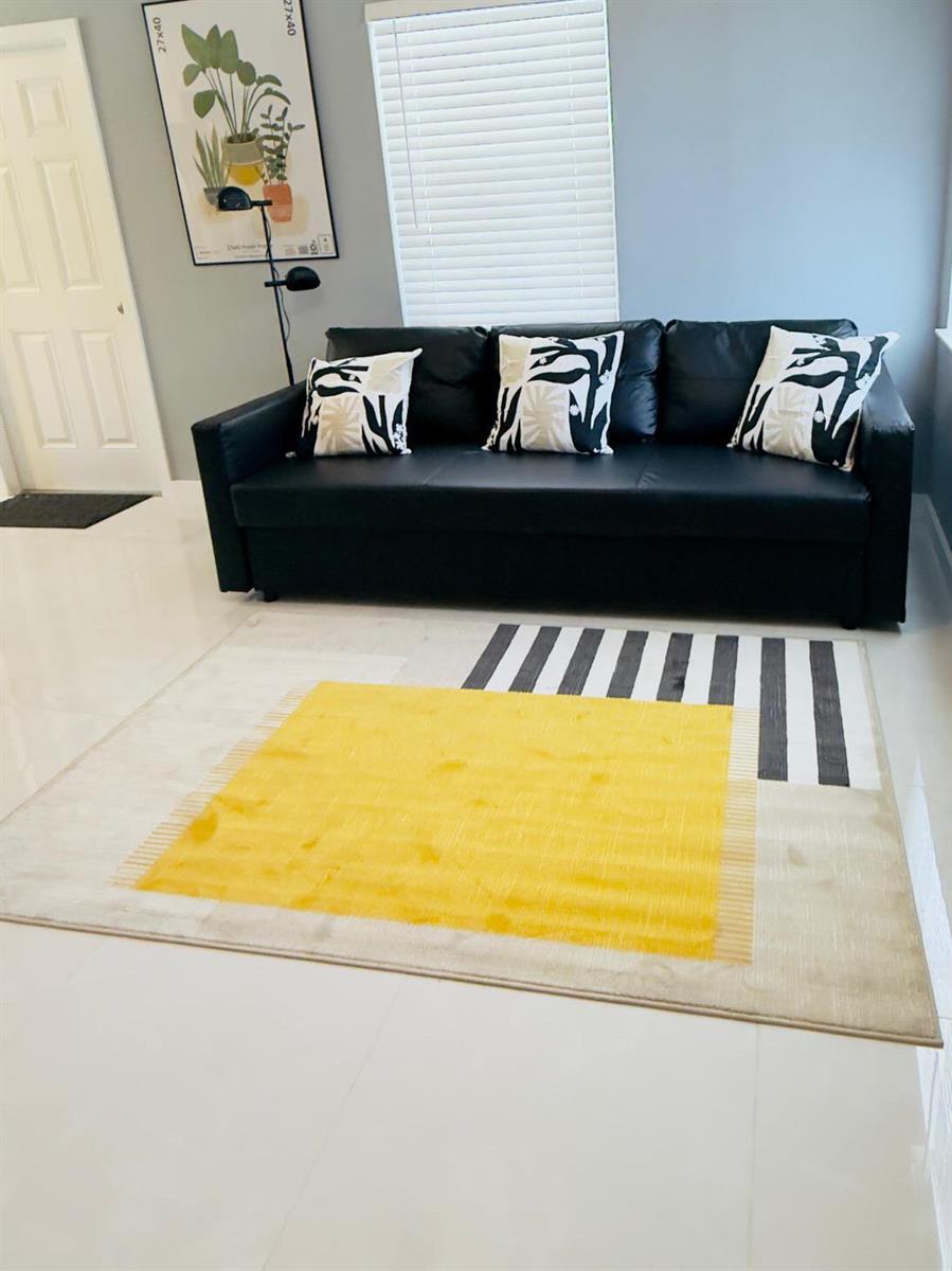 A living room features a black sofa, patterned throw pillows, and a yellow-accented area rug — 2533 NE 12th Terrace, Pompano Beach FL 33064, POMPANO BEACH, FL