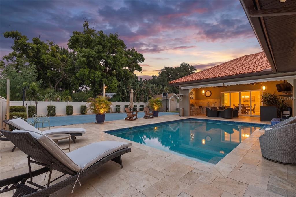 A backyard patio features a swimming pool, lounge chairs, and a covered outdoor dining area — 2101 W BEARSS AVENUE, TAMPA, FL