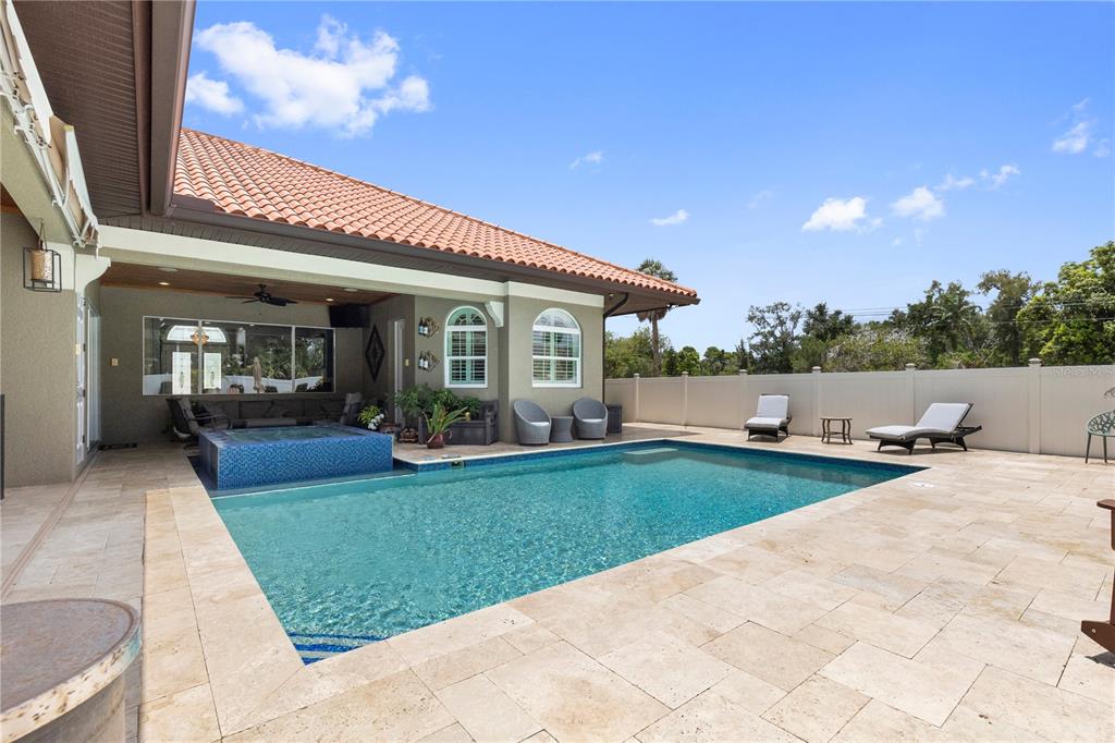A backyard features a swimming pool with an attached spa, stone patio, and covered porch — 2101 W BEARSS AVENUE, TAMPA, FL