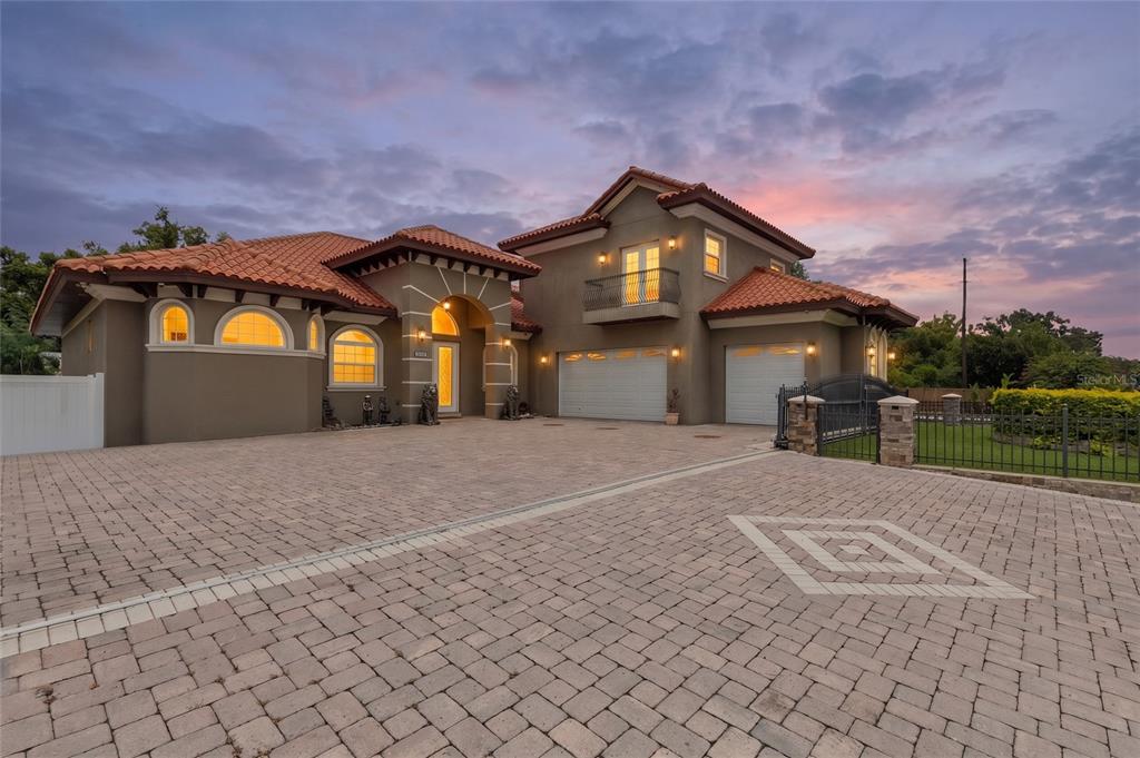 A two-story Mediterranean-style house with a tile roof, paved driveway, and attached three-car garage — 2101 W BEARSS AVENUE, TAMPA, FL