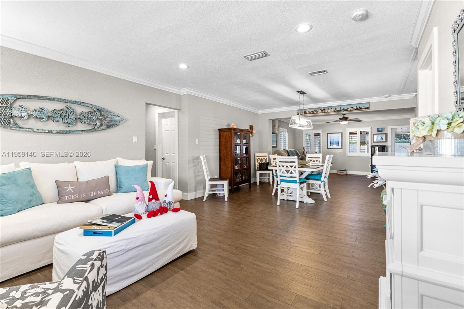 A living room and dining area feature white furniture, wood-look tile flooring, and coastal decor — 9390 SW 190th St, Cutler Bay FL 33157, CUTLER BAY, FL