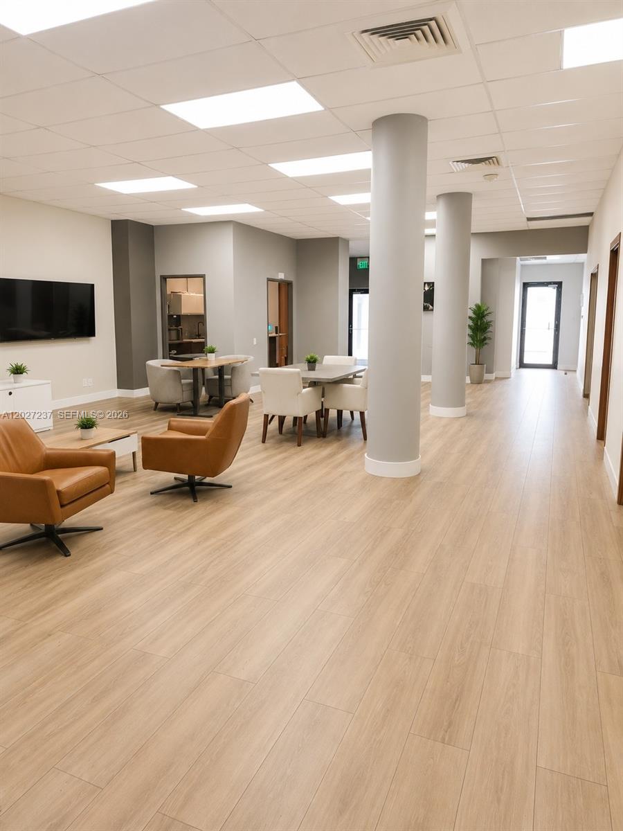 A modern office lounge features light wood flooring, two structural columns, and casual seating areas — 3505 S Ocean Dr, Hollywood FL 33019, HOLLYWOOD, FL