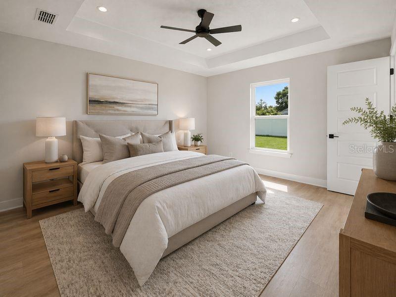 A bedroom features a tray ceiling with a fan, light-colored walls, and a wooden bed frame — 11081 SW 107TH PLACE, OCALA, FL