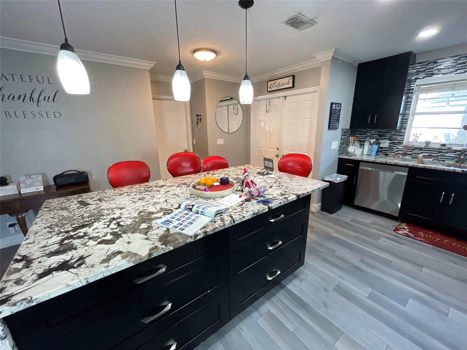 A kitchen features a large granite-topped island, black cabinetry, and red bar stools — 9020 Pine Springs Drive, Boca Raton FL 33428, BOCA RATON, FL