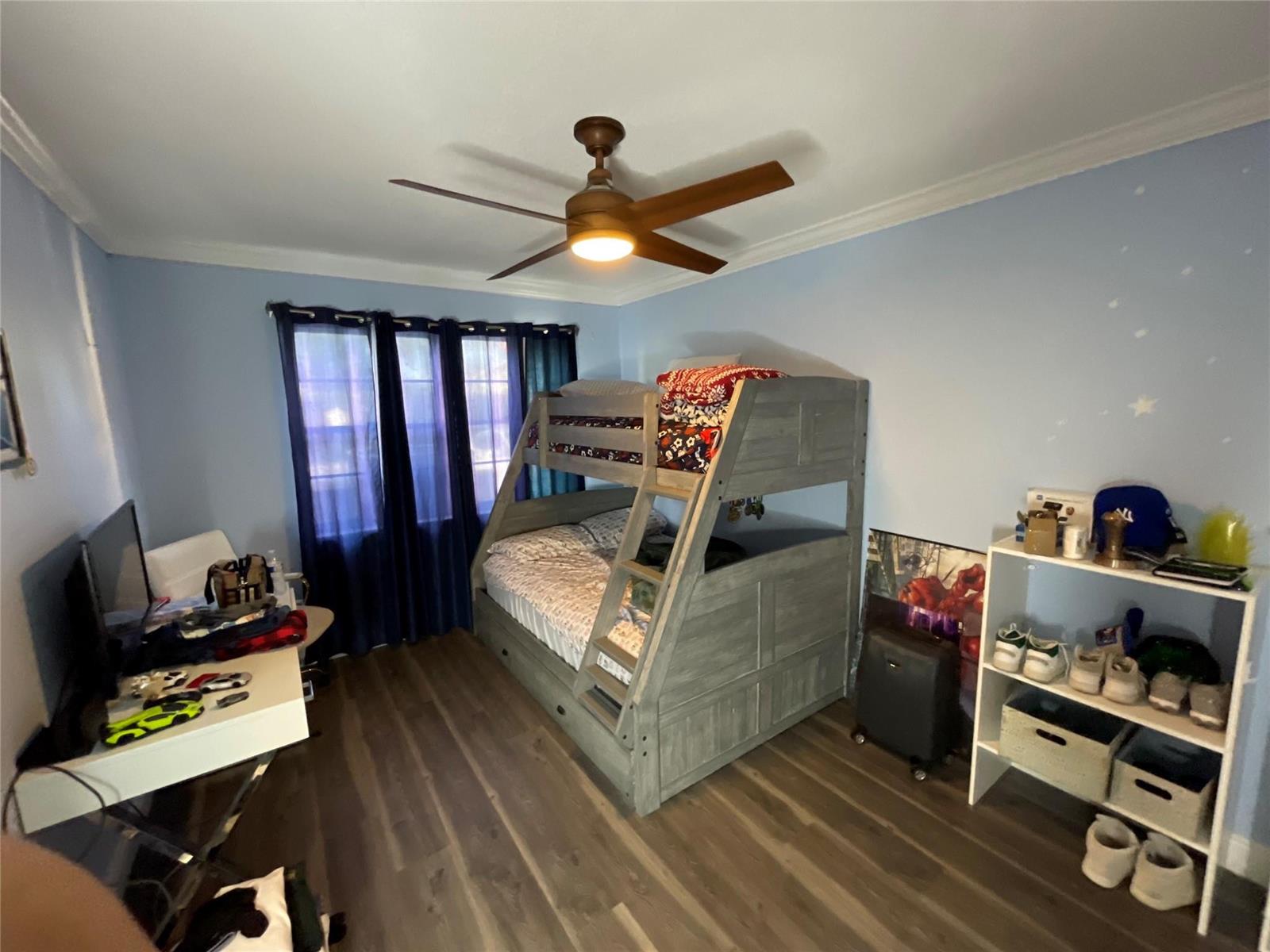 A bedroom features light blue walls, wood-look flooring, a gray bunk bed, and a ceiling fan — 9020 Pine Springs Drive, Boca Raton FL 33428, BOCA RATON, FL