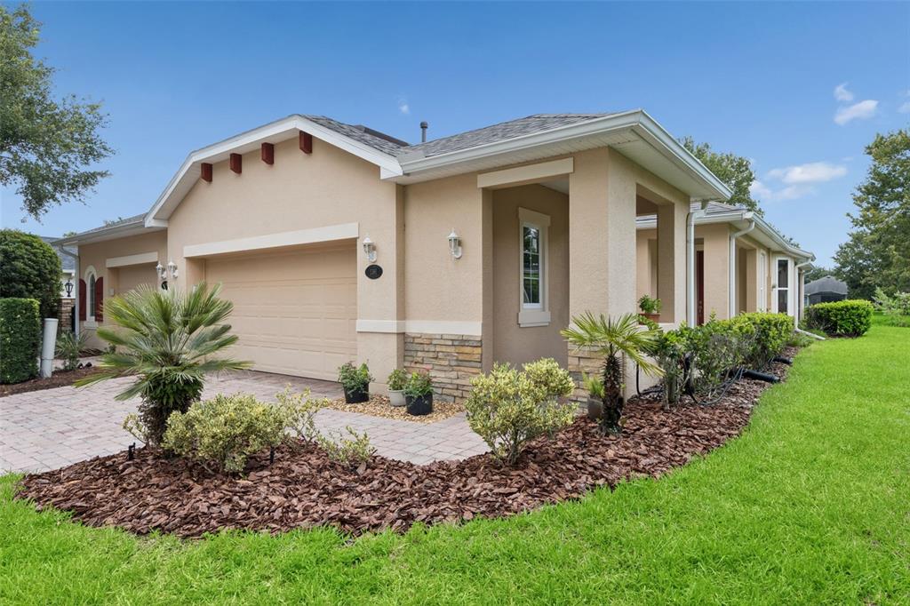A single-story house with a beige stucco exterior, stone accents, and a paved driveway — 1381 ABBOT WAY, DELAND, FL