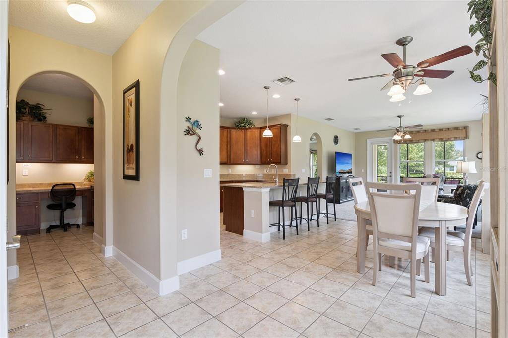An open-concept kitchen and dining area with tile floors, wooden cabinets, and a breakfast bar — 1381 ABBOT WAY, DELAND, FL