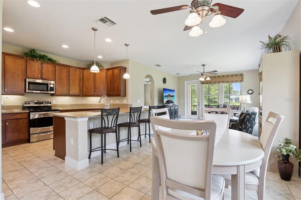 A kitchen with wood cabinets and a breakfast bar opens to a dining area — 1381 ABBOT WAY, DELAND, FL