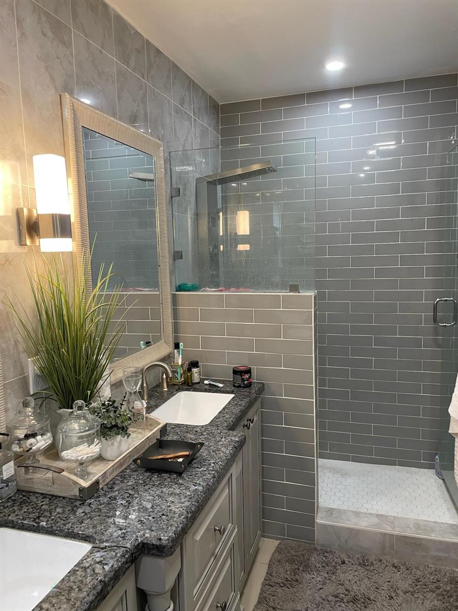 A bathroom features a granite vanity, gray subway tile walls, and a glass-enclosed walk-in shower — 7913 Kismet Street, Miramar FL 33023, MIRAMAR, FL