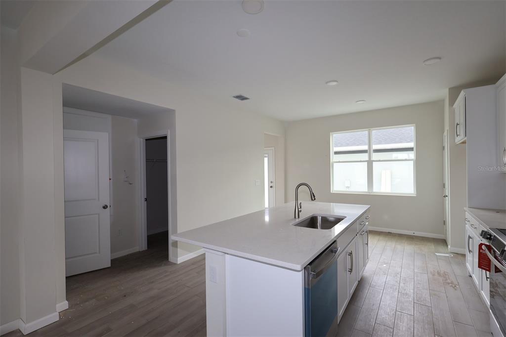 A kitchen with a white island, stainless steel sink, and light wood-look flooring — 1417 HYDE STREET, ST CLOUD, FL