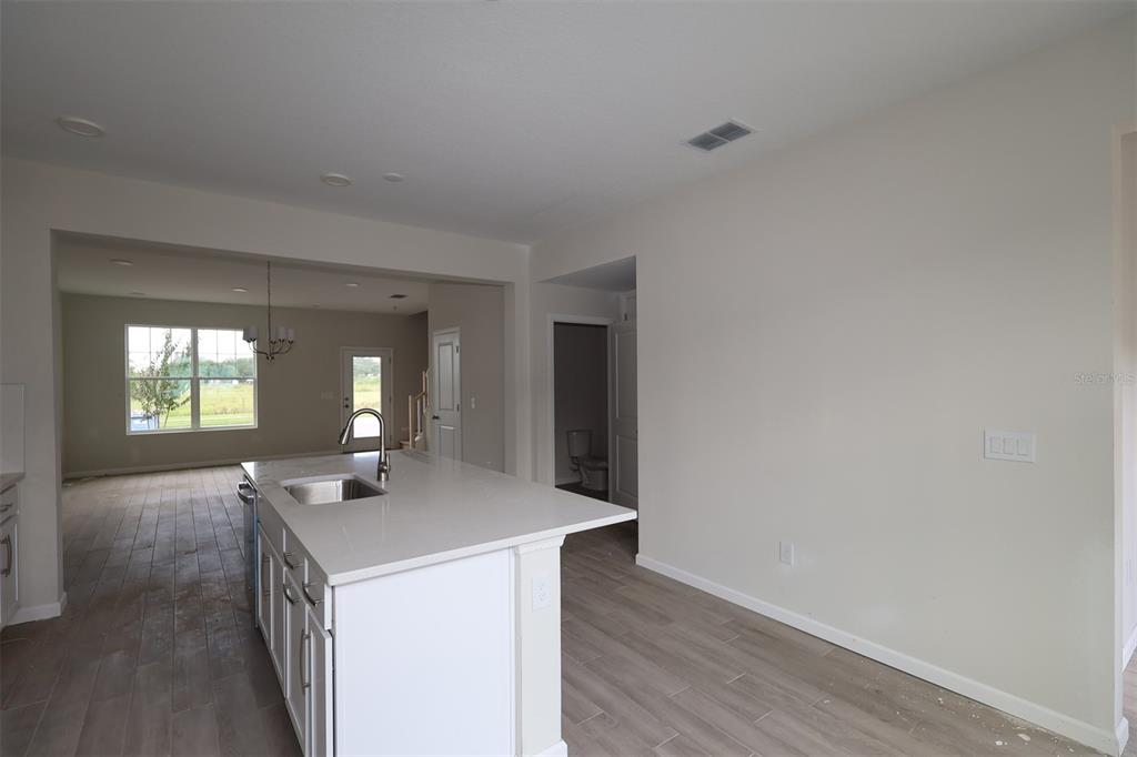A modern kitchen features white cabinets, stainless steel appliances, and a large central island — 1417 HYDE STREET, ST CLOUD, FL
