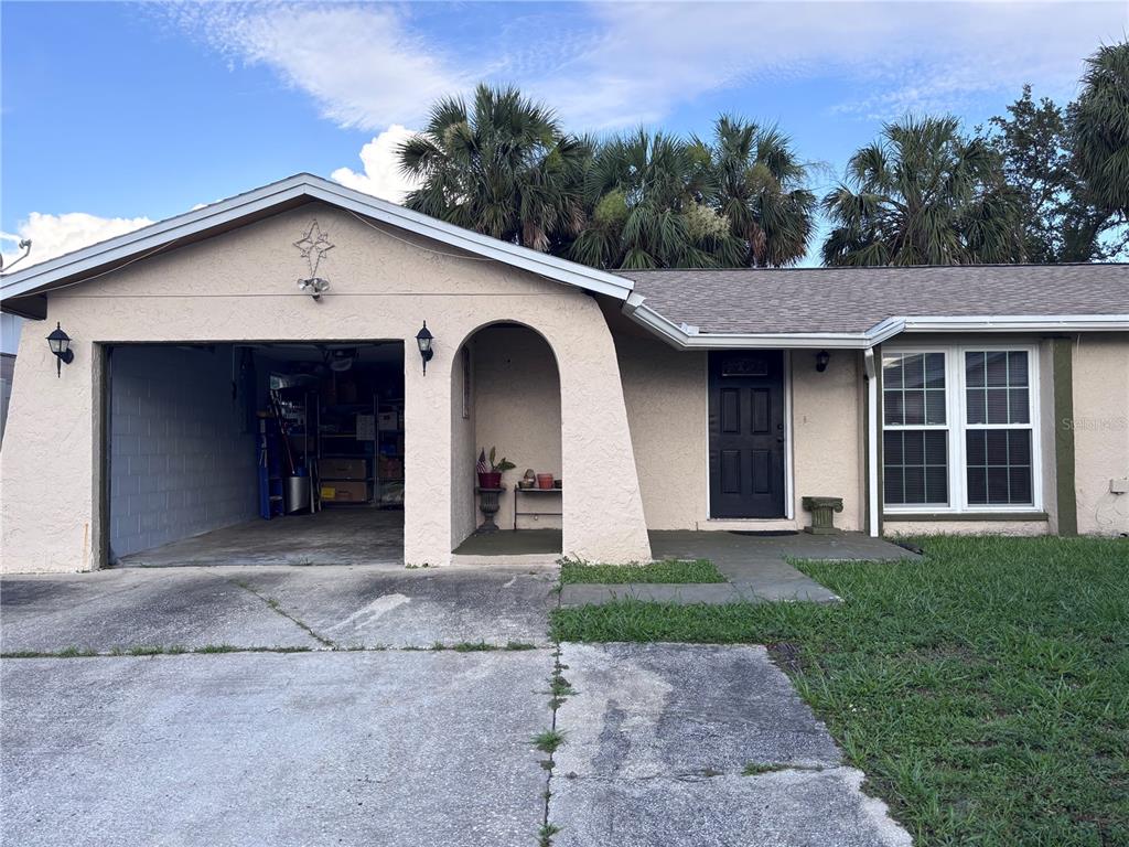 A single-story house with a garage, arched entryway, dark front door, and a concrete driveway — 10102 MISSY COURT, TAMPA, FL