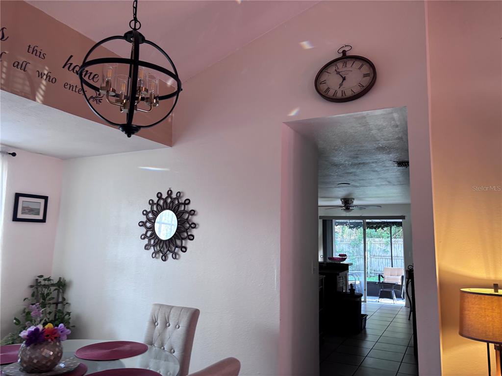 A dining area with a chandelier and wall clock leads into a room with sliding doors — 10102 MISSY COURT, TAMPA, FL