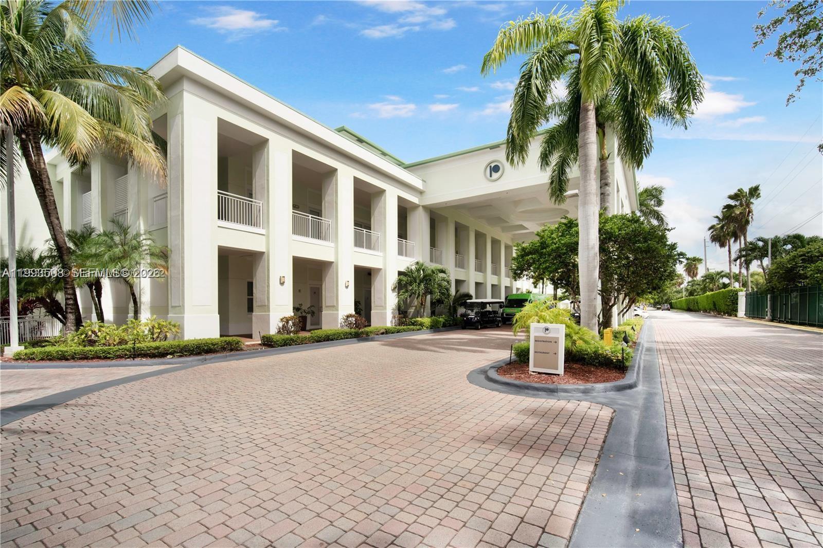 A paved driveway leads to the entrance of a multi-story building with palm trees — 5300 NW 87th Ave # 404, Doral FL 33178, DORAL, FL