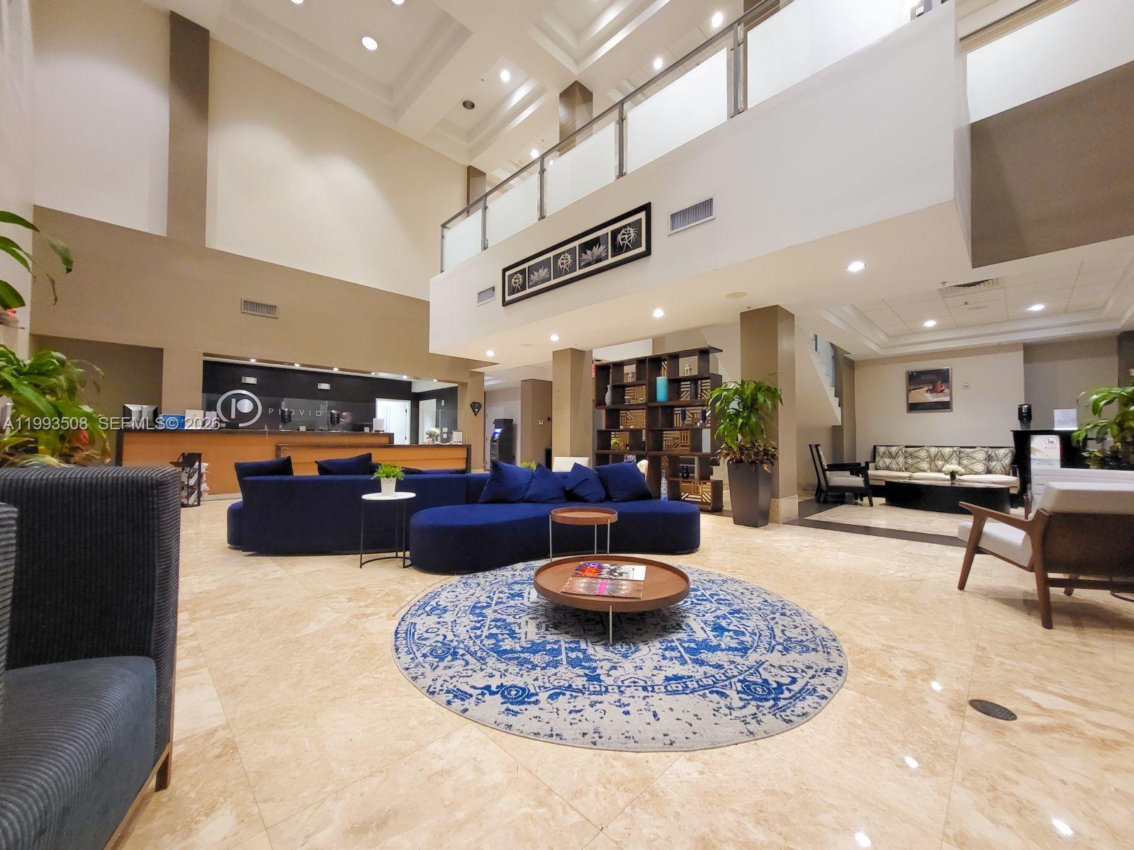A spacious hotel lobby features a large blue sectional sofa, marble floors, and high ceilings — 5300 NW 87th Ave # 404, Doral FL 33178, DORAL, FL