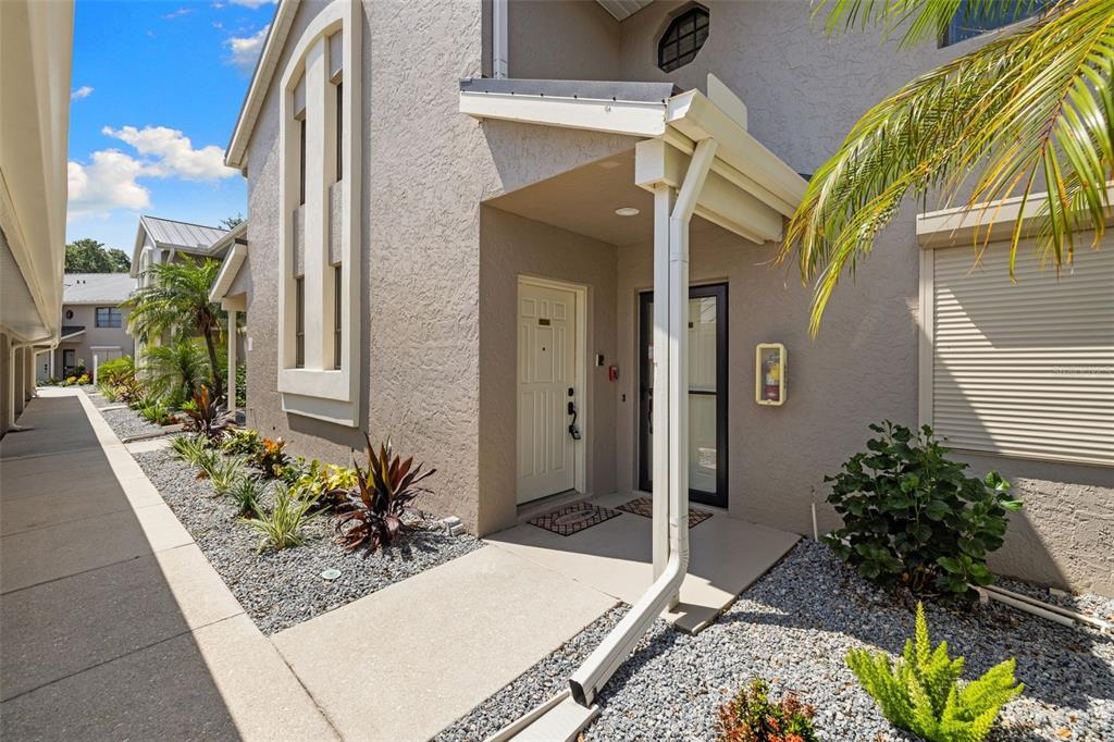 A beige two-story building exterior features a covered entryway, a concrete walkway, and landscaping — 1335 SAXONY CIRCLE UNIT 324, PUNTA GORDA, FL