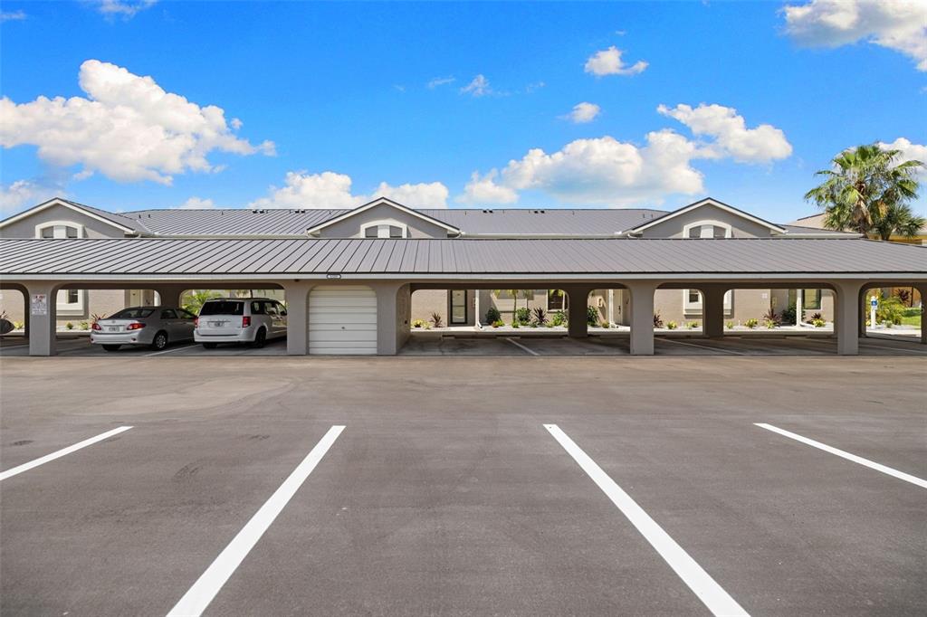 A parking lot with a long, covered carport structure in front of a residential building — 1335 SAXONY CIRCLE UNIT 324, PUNTA GORDA, FL